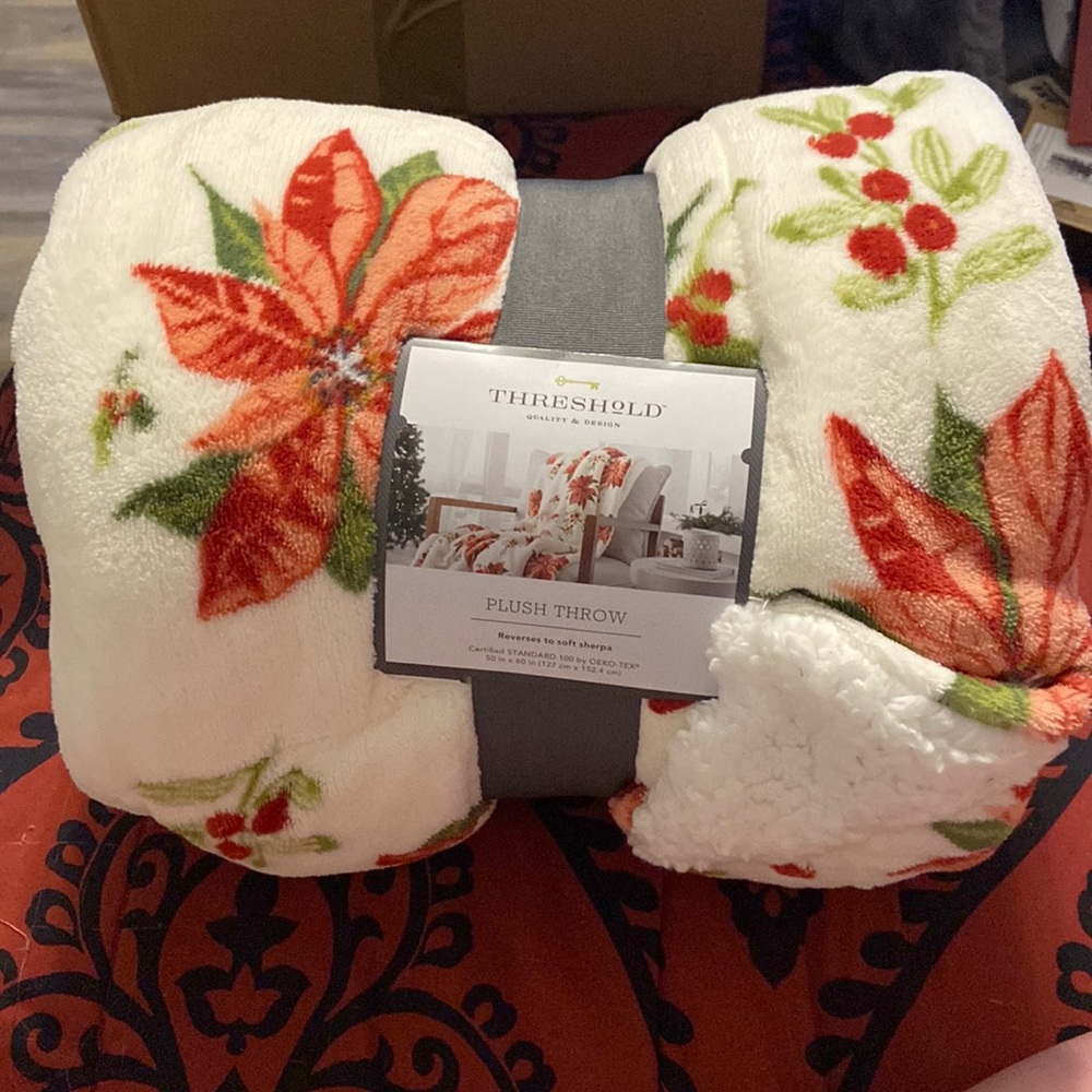 Plush thrown, white with red flowers and green leaves.